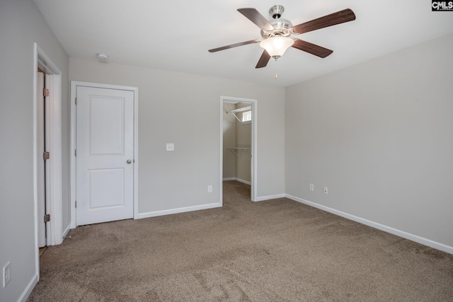 unfurnished bedroom featuring carpet floors, a spacious closet, a closet, and ceiling fan