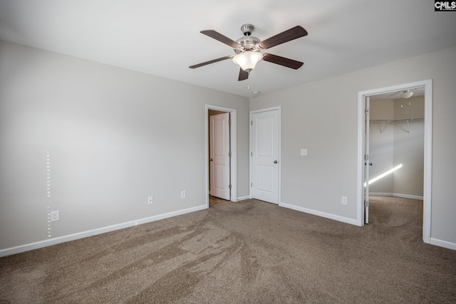 unfurnished bedroom featuring carpet, ceiling fan, a walk in closet, and a closet