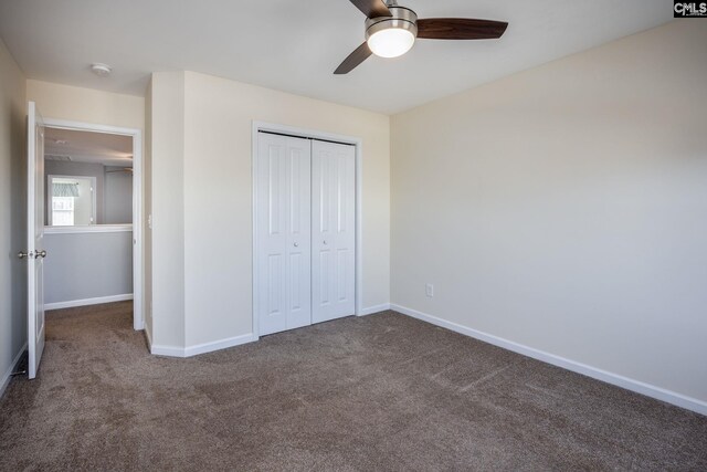 unfurnished bedroom featuring dark colored carpet, a closet, and ceiling fan