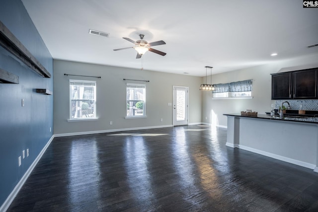 unfurnished living room with dark hardwood / wood-style flooring, ceiling fan, and sink