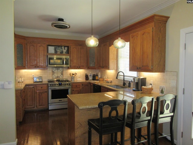 kitchen with kitchen peninsula, sink, decorative light fixtures, and appliances with stainless steel finishes