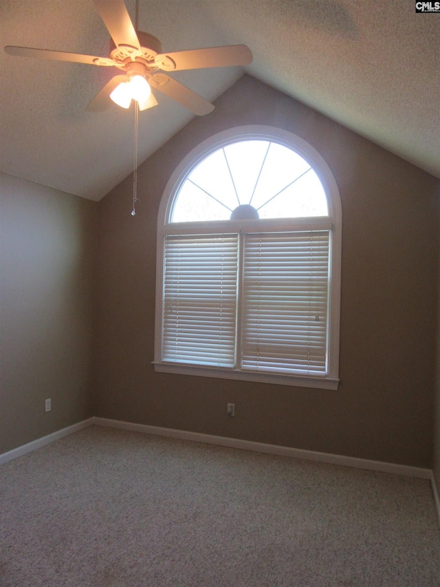 empty room featuring a textured ceiling, ceiling fan, carpet floors, and lofted ceiling