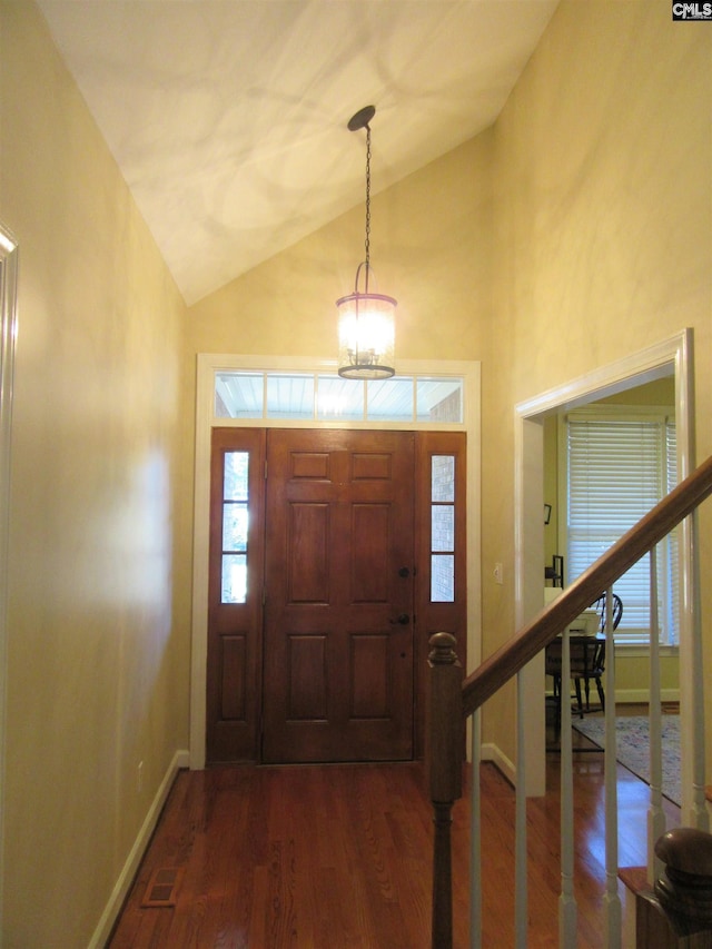 entrance foyer with dark hardwood / wood-style flooring, an inviting chandelier, and lofted ceiling