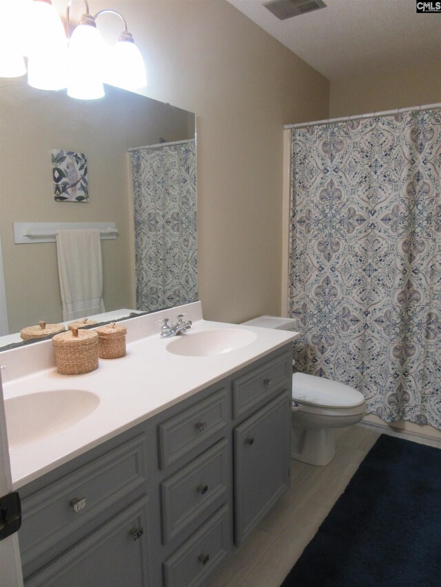 bathroom featuring an inviting chandelier, a shower with curtain, hardwood / wood-style floors, toilet, and vanity