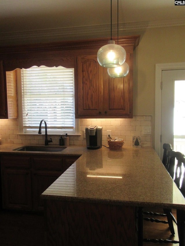 kitchen featuring decorative light fixtures, decorative backsplash, sink, and ornamental molding