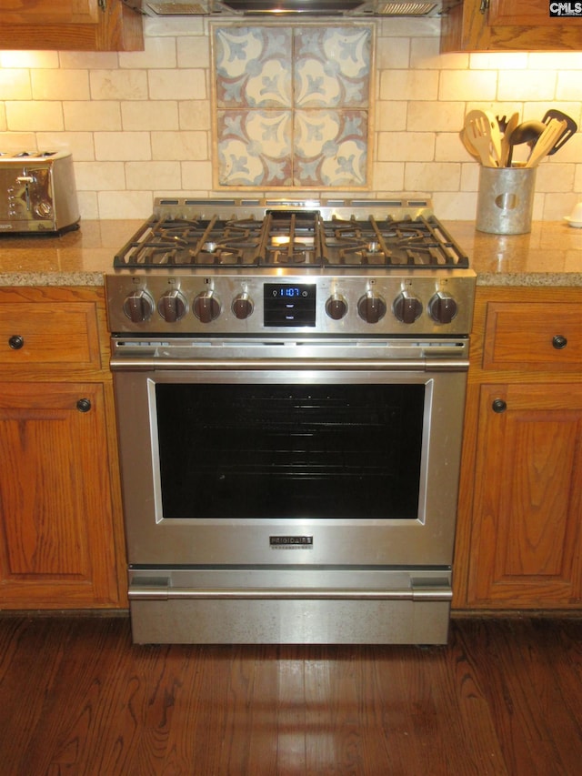 kitchen with decorative backsplash, light stone countertops, and high end stainless steel range