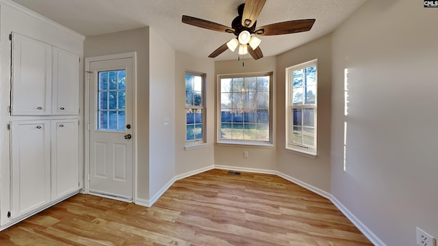 doorway to outside with ceiling fan, light hardwood / wood-style flooring, and a textured ceiling