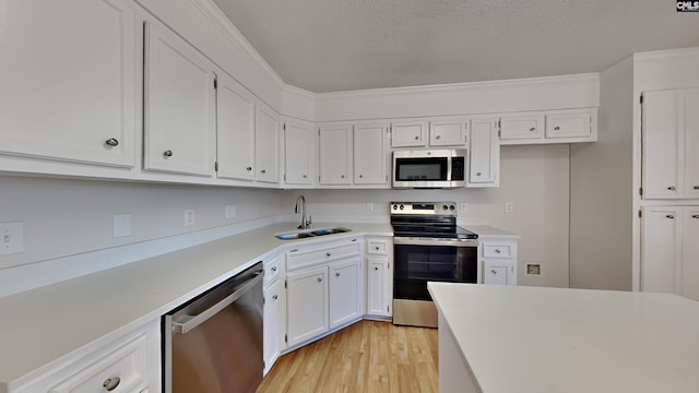 kitchen featuring a textured ceiling, stainless steel appliances, sink, light hardwood / wood-style floors, and white cabinetry