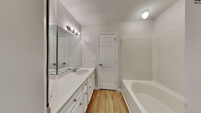 bathroom with a bathtub, vanity, wood-type flooring, and a textured ceiling