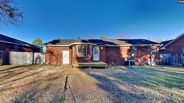 rear view of house featuring a wooden deck and a lawn