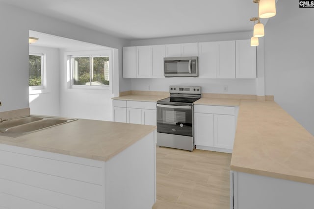 kitchen featuring pendant lighting, sink, white cabinets, and stainless steel appliances