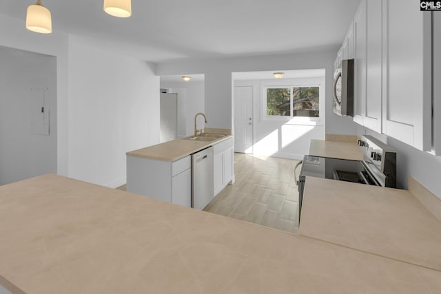 kitchen with sink, white cabinets, hanging light fixtures, and appliances with stainless steel finishes