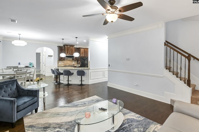 living room with dark hardwood / wood-style flooring, ceiling fan, crown molding, and sink