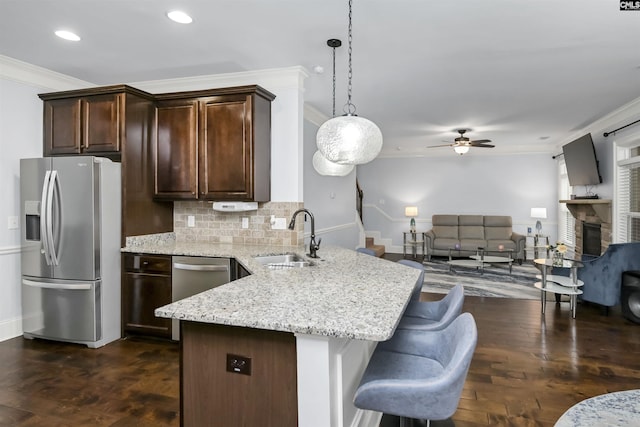 kitchen with dark brown cabinetry, ceiling fan, sink, stainless steel refrigerator with ice dispenser, and decorative light fixtures