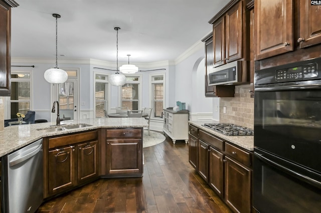 kitchen featuring light stone counters, dark brown cabinets, stainless steel appliances, sink, and hanging light fixtures