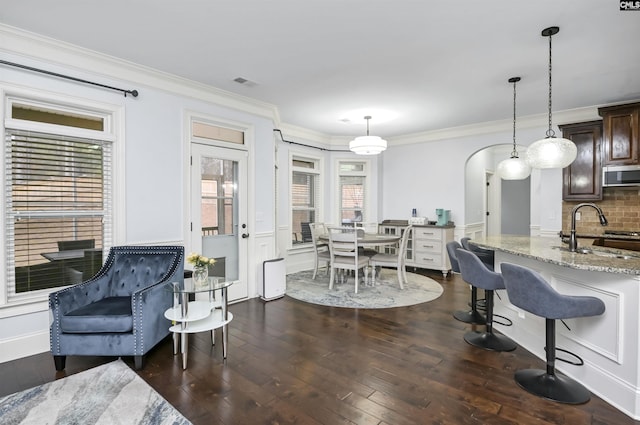 dining area with dark hardwood / wood-style floors, crown molding, and sink