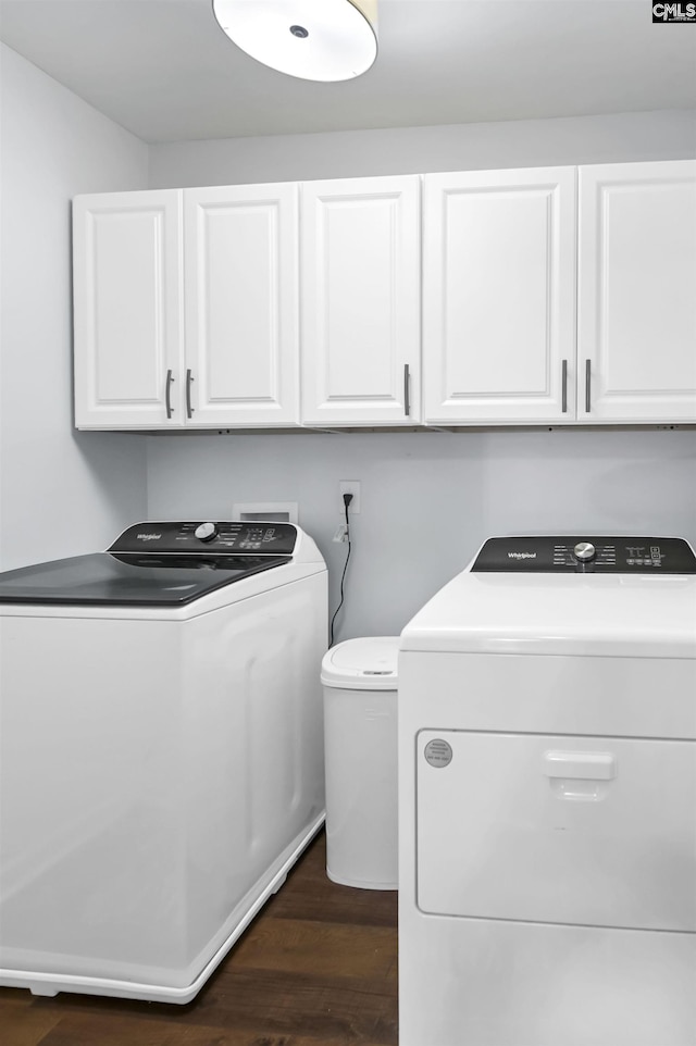 washroom with washing machine and dryer, dark hardwood / wood-style flooring, and cabinets