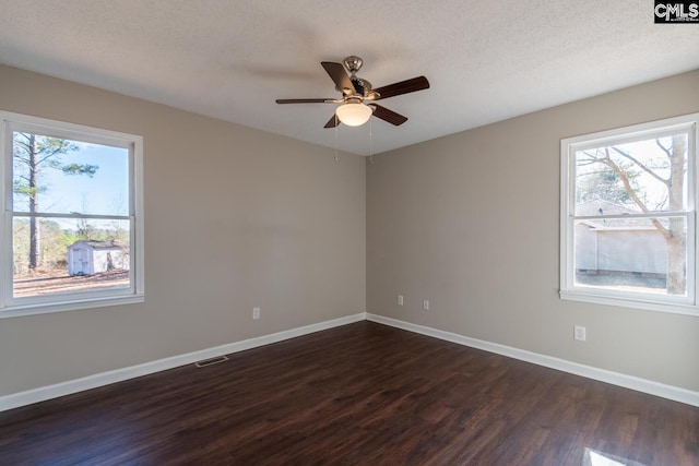 spare room featuring dark hardwood / wood-style floors, ceiling fan, and a wealth of natural light