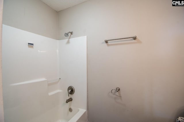 bathroom featuring  shower combination and a textured ceiling