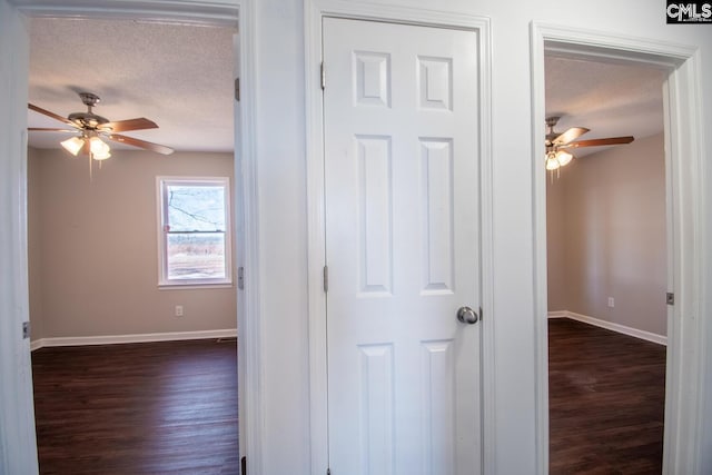 corridor with dark hardwood / wood-style flooring and a textured ceiling