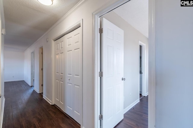 hallway featuring crown molding, dark wood-type flooring, and a textured ceiling