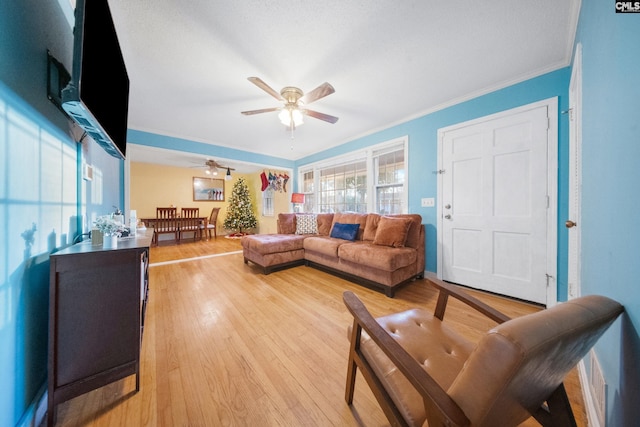 living room with light hardwood / wood-style floors, ceiling fan, and ornamental molding