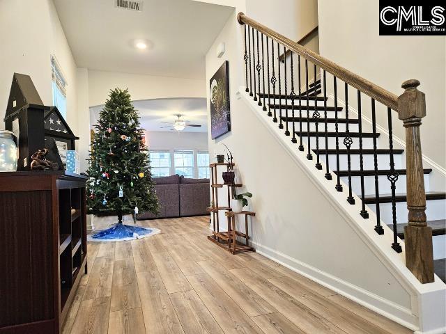 stairway featuring visible vents, a ceiling fan, baseboards, and wood-type flooring