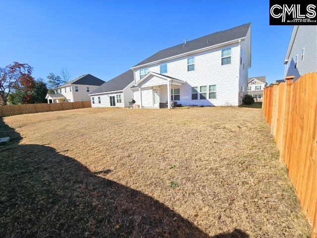 back of property featuring a yard and fence