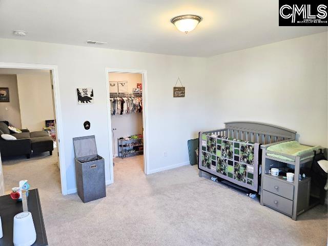 carpeted bedroom featuring visible vents, baseboards, a closet, and a walk in closet