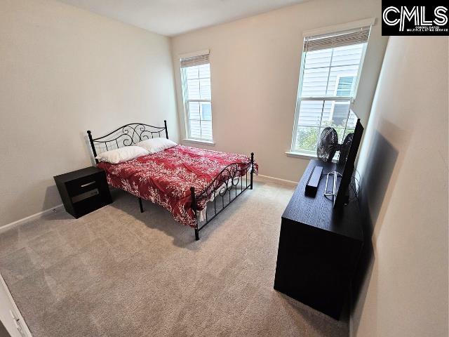 bedroom with light colored carpet and baseboards