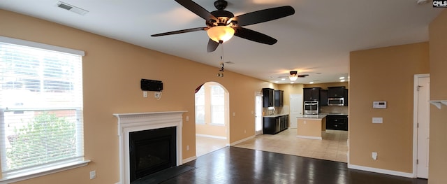 unfurnished living room with wood-type flooring, a wealth of natural light, and ceiling fan