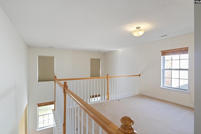 hallway featuring carpet flooring and a textured ceiling