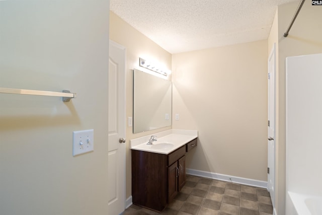 bathroom with a bath, a textured ceiling, and vanity