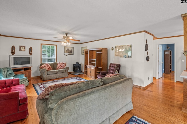 living room featuring a wood stove, hardwood / wood-style flooring, ceiling fan, ornamental molding, and a textured ceiling