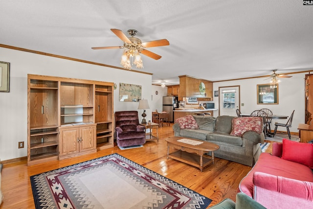 living room with a textured ceiling, light wood-type flooring, ceiling fan, and ornamental molding