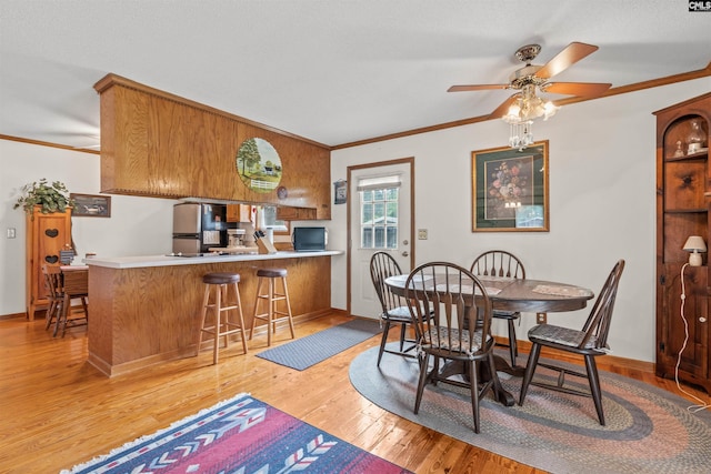 dining area featuring ceiling fan, ornamental molding, and light hardwood / wood-style flooring