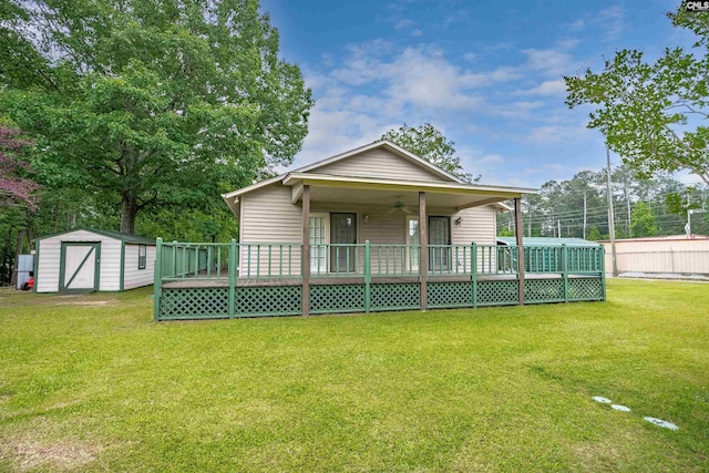 back of property with a lawn, a wooden deck, ceiling fan, and a storage unit