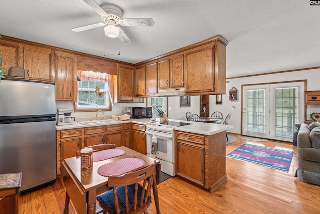 kitchen featuring stainless steel refrigerator, ceiling fan, sink, kitchen peninsula, and white stove