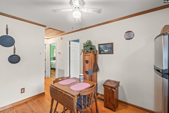 dining area with a textured ceiling, light wood-type flooring, ceiling fan, and crown molding