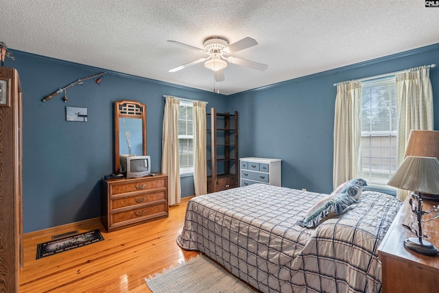 bedroom featuring ceiling fan, crown molding, light wood-type flooring, and a textured ceiling