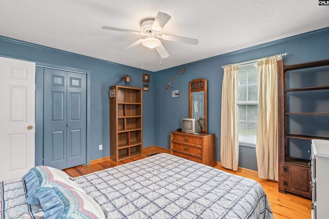 bedroom featuring a textured ceiling, light hardwood / wood-style flooring, a closet, and ceiling fan