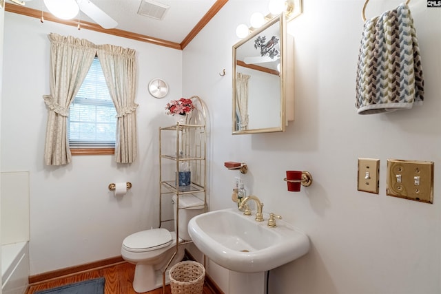 bathroom with ornamental molding, sink, wood-type flooring, toilet, and a tub