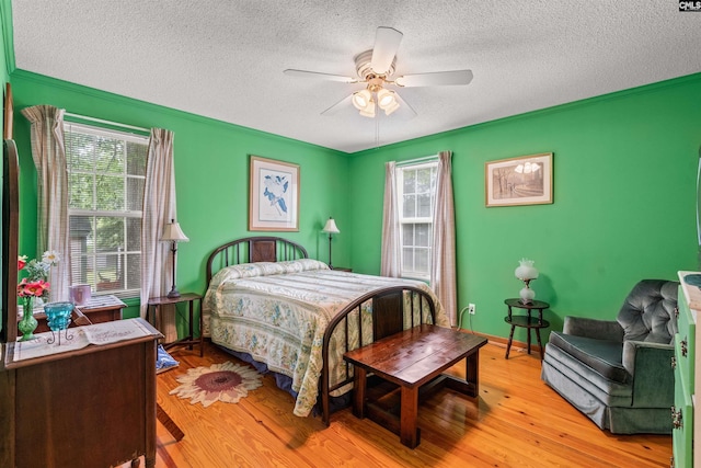 bedroom featuring ceiling fan, light hardwood / wood-style floors, a textured ceiling, and multiple windows