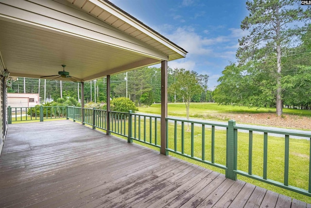 wooden terrace featuring ceiling fan and a yard