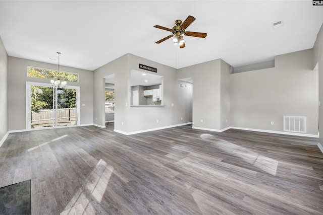 unfurnished living room featuring a towering ceiling, wood-type flooring, and ceiling fan with notable chandelier