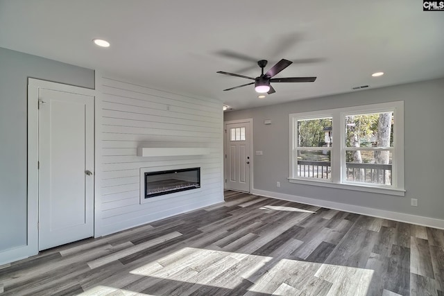 unfurnished living room with ceiling fan, a fireplace, and wood-type flooring