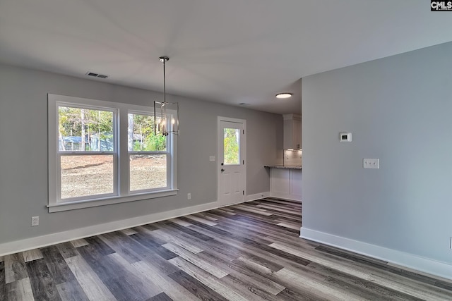 unfurnished dining area featuring dark hardwood / wood-style floors and an inviting chandelier