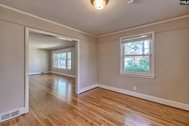 empty room featuring crown molding, light hardwood / wood-style flooring, and a healthy amount of sunlight