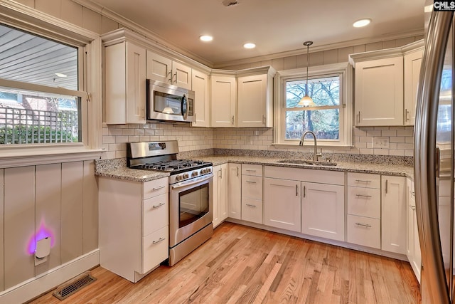 kitchen with white cabinets, sink, appliances with stainless steel finishes, and light hardwood / wood-style flooring