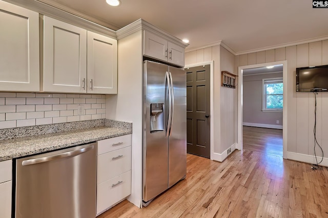 kitchen featuring white cabinets, light hardwood / wood-style flooring, ornamental molding, light stone counters, and stainless steel appliances